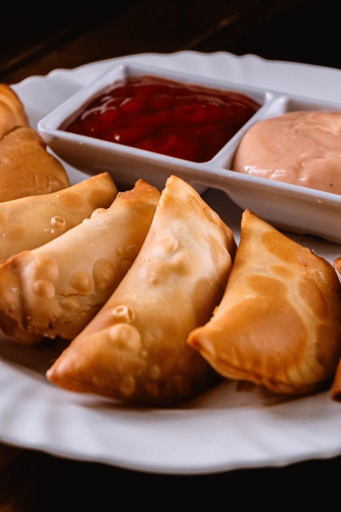 crispy-empanadas-with-dipping-sauces-on-plate-28902899 A plate of golden-brown empanadas served with red and pink dipping sauces.
